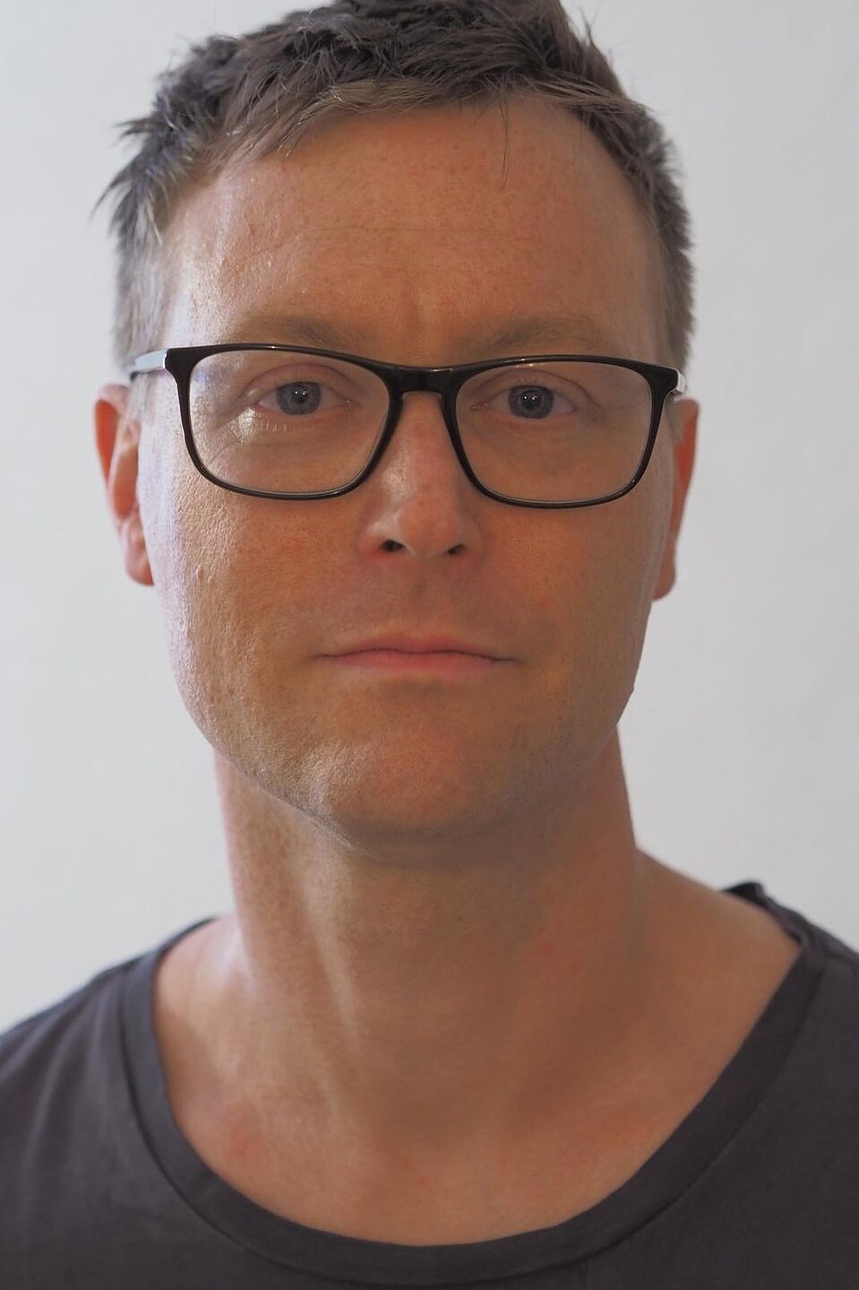 Dr. Rul von Stülpnagel Porträtfoto von Dr. Rul von Stülpnagel: Mann mit kurzen braunen Haaren, schwarzer Brille und grauem T-Shirt vor weißem Hintergrund.